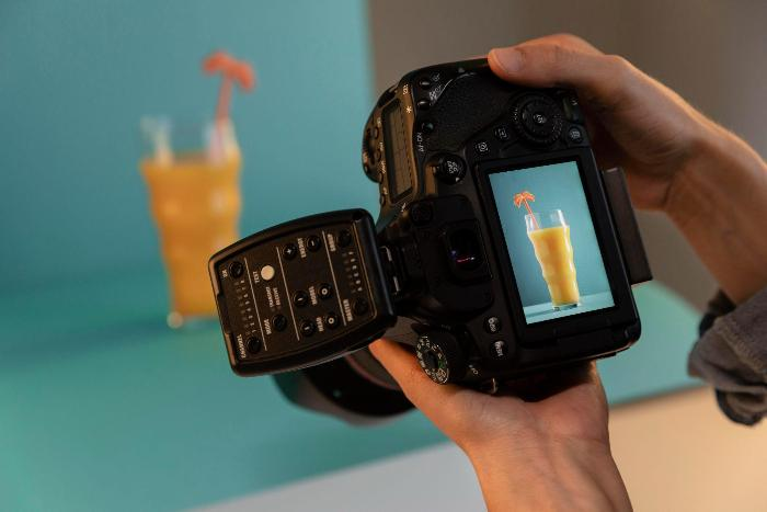 Hands holding a camera displaying a photo of a drink on the screen